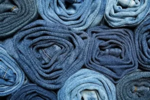 Rouleaux de tissu denim en armure sergé montrant différentes épaisseurs et nuances de bleu