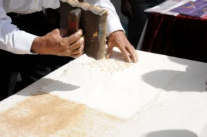 Artisan imprimant un tissu en coton au blockprint avec un tampon en bois en Inde