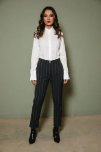 Femme portant une chemise blanche col classique et un pantalon tailleur rayé illustrant les codes du style classique en couture