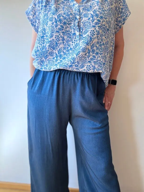 Pantalon Singapour d'Ikatee porté de face avec un chemisier fleuri bleu et blanc
